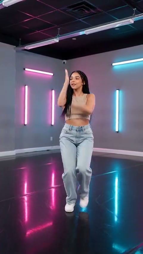 Standbild eines externen Videos mit einer einzelnen tanzenden Person in Jeans und weißen Turnschuhen, die im pink-cyanfarbenen Neonstudio einen Arm und einen Fuß hebt